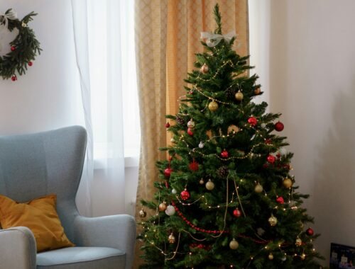 Árvore de Natal tradicional com luzes amarelas e enfeites vermelhos e dourados.